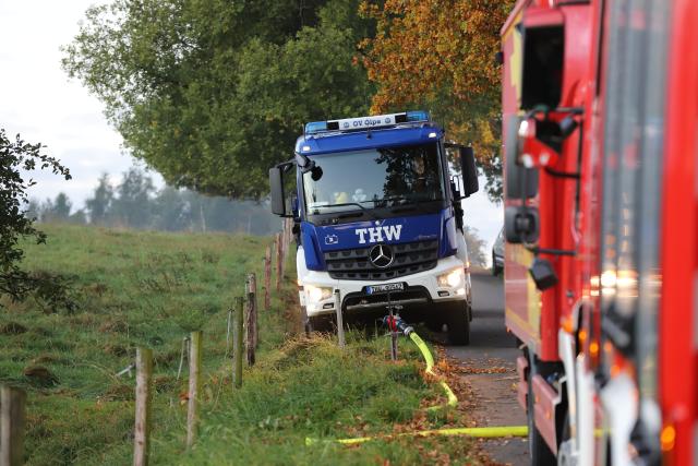 14 October 2025, North Rhine-Westphalia, Much: A THW vehicle is parked at the scene where a warehouse with vintage cars had caught fire. According to the fire department, they brought the fire under control, but were still at the scene early in the morning. Photo: Sascha Thelen/dpa