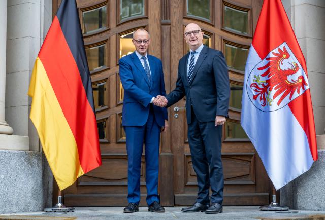 14 October 2025, Brandenburg, Potsdam: German Chancellor Friedrich Merz (L) is welcomed by Dietmar Woidke, Minister President of Brandenburg, at the cabinet meeting in front of the State Chancellery of Brandenburg. Photo: Michael Kappeler/dpa