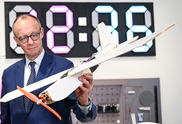 14 October 2025, Brandenburg, Potsdam: German Chancellor Friedrich Merz holds a model of an airplane at the Maker Universe Project Studio of the Hasso Plattner Institute during his inaugural visit to Brandenburg. Photo: Britta Pedersen/dpa Pool/dpa