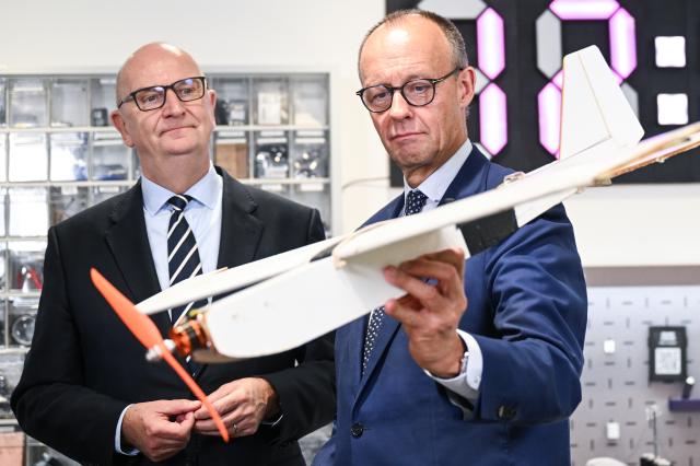 14 October 2025, Brandenburg, Potsdam: German Chancellor Friedrich Merz holds a model of an airplane at the Maker Universe Project Studio of the Hasso Plattner Institute during his inaugural visit to Brandenburg. Photo: Britta Pedersen/dpa Pool/dpa