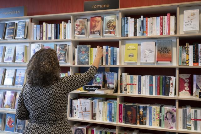 FILED - 25 September 2022, Hesse, Frankfurt/Main: A woman takes a novel from the shelf in the "Buecher im Bogen" bookshop. Photo: Boris Roessler/dpa