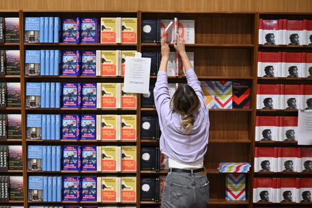 14 October 2025, Hesse, Frankfurt/Main: An employee fills the shelves with books at the S. Fischer publishers' stand at the Frankfurt Book Fair during the set-up. Photo: Arne Dedert/dpa
