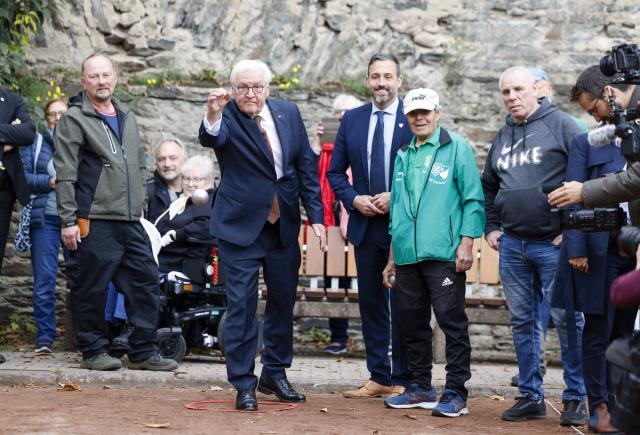 14 October 2025, Rhineland-Palatinate, Andernach: German President Frank-Walter Steinmeier (C) plays a game of boules with other boules players during his tour of the palace gardens. Photo: Thomas Banneyer/dpa
