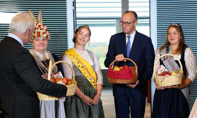 15 October 2025, Berlin: German Chancellor Friedrich Merz (2-R) and Alois Rainer (L), Federal Minister of Food, Agriculture and Home Affairs, hold baskets of apples presented to them by Ella-Maxim Weilert (L-R), Emelie Witzigmann and Lara Sophie Baur before the cabinet meeting. Apple and blossom queens from various regions of Germany distributed apple baskets to the members of the Federal Government before the German Cabinet meeting in the Federal Chancellery. Photo: Michael Kappeler/dpa