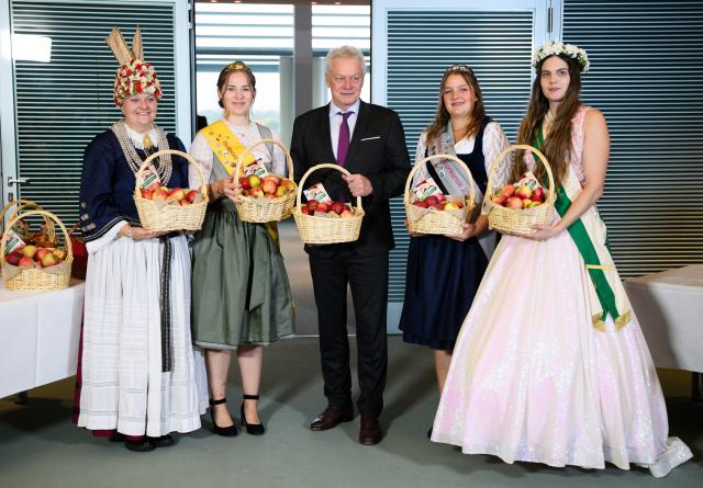 15 October 2025, Berlin: Alois Rainer (C), German Minister of Food, Agriculture and Home Affairs, holds a basket of apples before the cabinet meeting, which was presented to him by Ella-Maxim Weilert (L-R), Emelie Witzigmann, Lara Sophie Baur and Alida-Nadine Kuehne. Apple and blossom queens from various regions of Germany distributed apple baskets to the members of the Federal Government before the German Cabinet meeting at the German Chancellery. Photo: Michael Kappeler/dpa