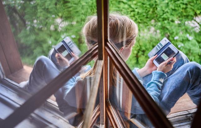 FILED - 28 May 2022, Berlin: A boy sits at the window and looks at his cell phone. EU proposals aimed at protecting minors from sexual abuse online have divided the bloc, as opponents cite privacy concerns. Advocacy groups warn that the inability to move forward with the legislation is leaving children vulnerable. Photo: Annette Riedl/dpa