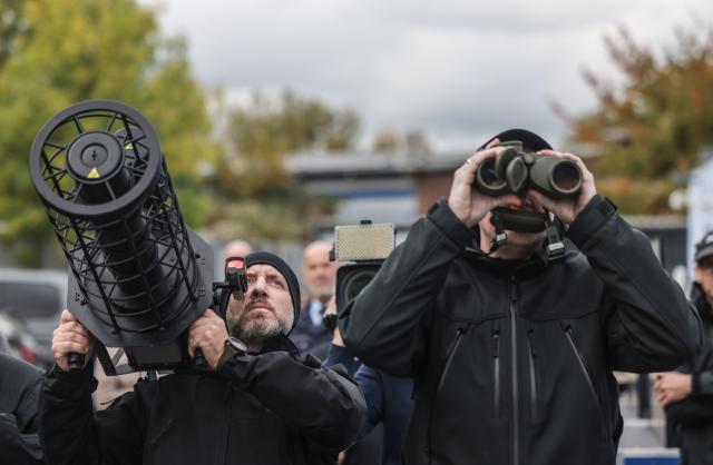 15 October 2025, North Rhine-Westphalia, Duesseldorf: Drone defense police officers take aim at a drone with a jammer (L) and binoculars (R) during the North Rhine-Westphalia police presentation of their drone defense capabilities. Photo: Oliver Berg/dpa