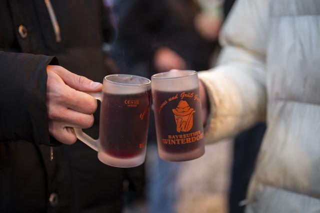 15 October 2025, Bavaria, Bayreuth: Two visitors to the Bayreuth Winter Village drink mulled wine. Photo: Daniel Vogl/dpa