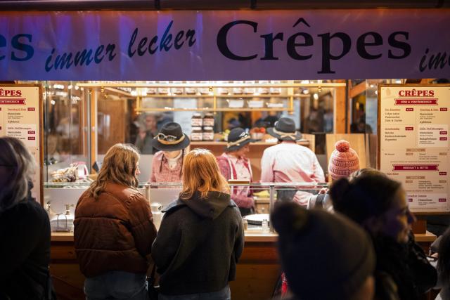 15 October 2025, Bavaria, Bayreuth: People stand at a crepe stand at the opening of the Bayreuth Winter Village. Photo: Daniel Vogl/dpa