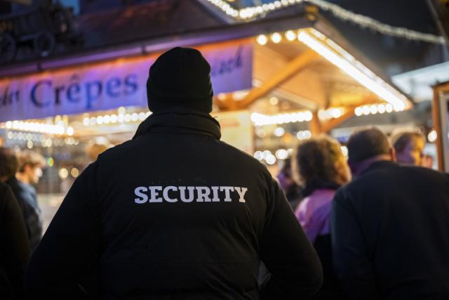 15 October 2025, Bavaria, Bayreuth: A security guard walks across the grounds of the Bayreuth Winter Village at its opening. Photo: Daniel Vogl/dpa