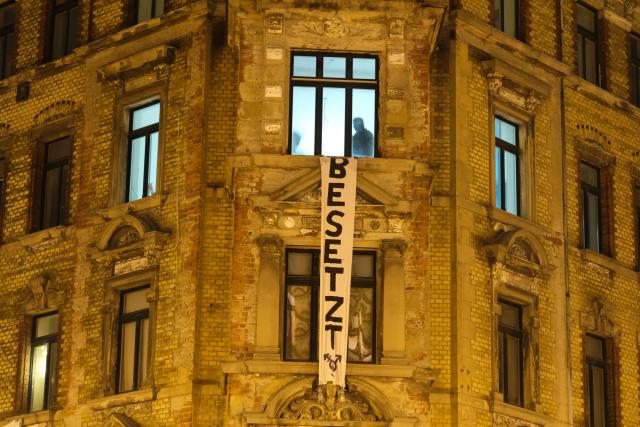 15 October 2025, Saxony, Leipzig: Police officers in a vacant building in the east of Leipzig, with a banner reading "Besetzt" (occupied) hanging on the facade. Left-wing activists have occupied the building for the third time in just few days. Photo: Sebastian Willnow/dpa