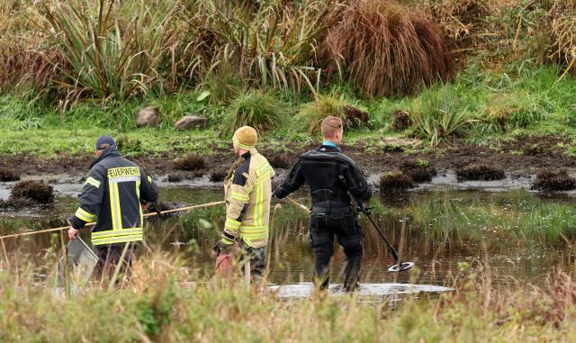 17 October 2025, Mecklenburg-Western Pomerania, Klein Upahl: At the site where eight-year-old Fabian from Guestrow was found dead in a small pond near Klein Upahl, the fire department pumps out the water while a police officer is in action with a detector. According to preliminary autopsy results, the primary school pupil was the victim of a violent crime. Photo: Bernd Wüstneck/dpa