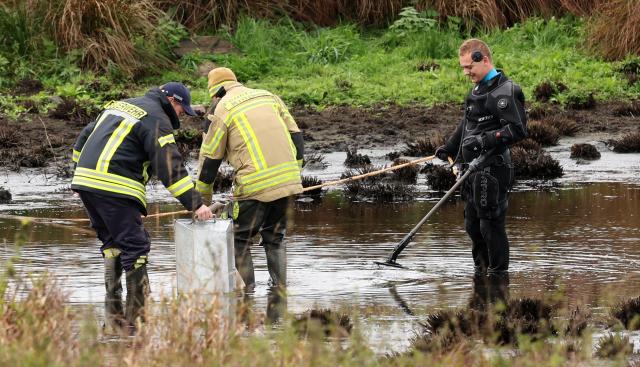 17 October 2025, Mecklenburg-Western Pomerania, Klein Upahl: At the site where eight-year-old Fabian from Guestrow was found dead in a small pond near Klein Upahl, the fire department pumps out the water while a police officer is in action with a detector. According to preliminary autopsy results, the primary school pupil was the victim of a violent crime. Photo: Bernd Wüstneck/dpa