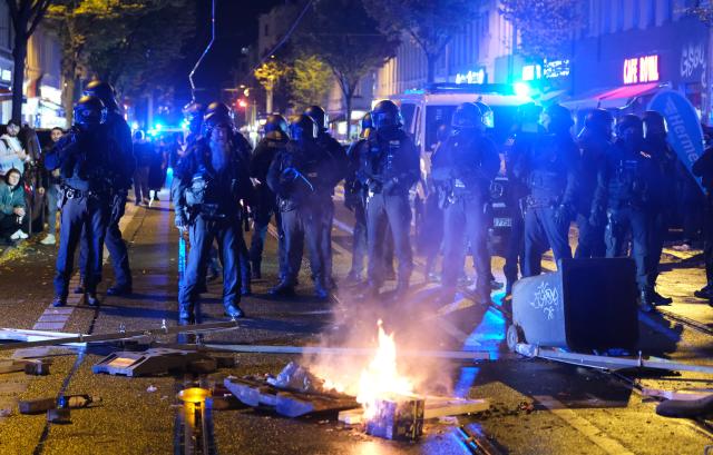 17 October 2025, Saxony, Leipzig: Police officers stand in front of burning objects on Eisenbahnstrasse as Left-wing activists stage a spontaneous demonstration to protest against the eviction of squats. Photo: Sebastian Willnow/dpa