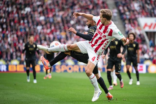 18 October 2025, North Rhine-Westphalia, Cologne: Cologne's Timo Huebers (R) and Augsburg's Elias Saad battle for the ball during the German Bundesliga soccer match between 1. FC Cologne and FC Augsburg at RheinEnergieStadion. Photo: Marius Becker/dpa - WICHTIGER HINWEIS: Gemäß den Vorgaben der DFL Deutsche Fußball Liga bzw. des DFB Deutscher Fußball-Bund ist es untersagt, in dem Stadion und/oder vom Spiel angefertigte Fotoaufnahmen in Form von Sequenzbildern und/oder videoähnlichen Fotostrecken zu verwerten bzw. verwerten zu lassen.