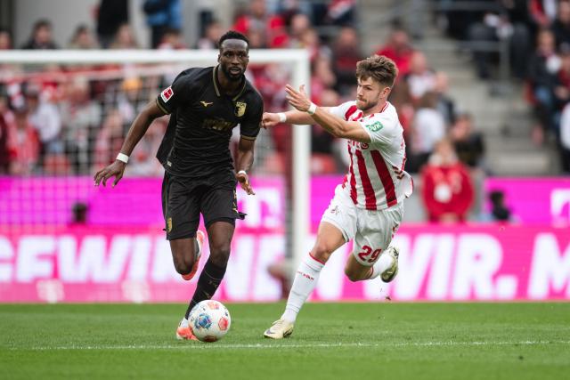 18 October 2025, North Rhine-Westphalia, Cologne: Cologne's Jan Thielmann (R) and Augsburg's Chrislain Matsima battle for the ball during the German Bundesliga soccer match between 1. FC Cologne and FC Augsburg at RheinEnergieStadion. Photo: Marius Becker/dpa - WICHTIGER HINWEIS: Gemäß den Vorgaben der DFL Deutsche Fußball Liga bzw. des DFB Deutscher Fußball-Bund ist es untersagt, in dem Stadion und/oder vom Spiel angefertigte Fotoaufnahmen in Form von Sequenzbildern und/oder videoähnlichen Fotostrecken zu verwerten bzw. verwerten zu lassen.