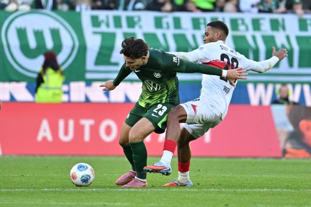 18 October 2025, Lower Saxony, Wolfsburg: Stuttgart's Nikolas Nartey (R) and Wolfsburg's Jonas Wind battle for the ball during the German Bundesliga soccer match between VfL Wolfsburg and VfB Stuttgart at Volkswagen Arena. Photo: Swen Pförtner/dpa - WICHTIGER HINWEIS: Gemäß den Vorgaben der DFL Deutsche Fußball Liga bzw. des DFB Deutscher Fußball-Bund ist es untersagt, in dem Stadion und/oder vom Spiel angefertigte Fotoaufnahmen in Form von Sequenzbildern und/oder videoähnlichen Fotostrecken zu verwerten bzw. verwerten zu lassen.