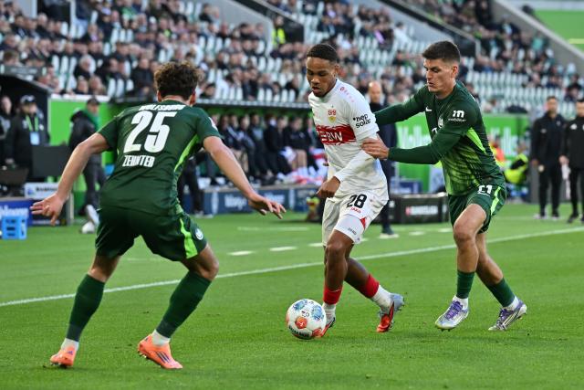 18 October 2025, Lower Saxony, Wolfsburg: Stuttgart's Nikolas Nartey (C) battles for the ball with Wolfsburg's Adam Daghim (L) and Aaron Zehnter during the German Bundesliga soccer match between VfL Wolfsburg and VfB Stuttgart at Volkswagen Arena. Photo: Swen Pförtner/dpa - WICHTIGER HINWEIS: Gemäß den Vorgaben der DFL Deutsche Fußball Liga bzw. des DFB Deutscher Fußball-Bund ist es untersagt, in dem Stadion und/oder vom Spiel angefertigte Fotoaufnahmen in Form von Sequenzbildern und/oder videoähnlichen Fotostrecken zu verwerten bzw. verwerten zu lassen.