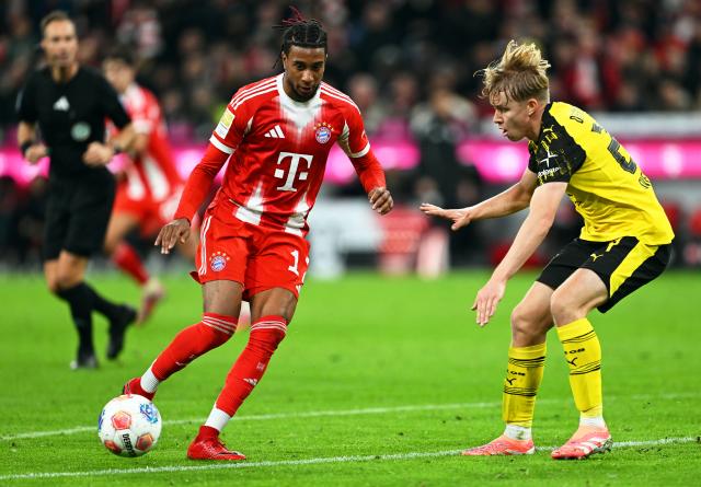 18 October 2025, Bavaria, Munich: Bayern Munich's Michael Olise (L) and Borussia Dortmund's Daniel Svensson battle for the ball during the German Bundesliga soccer match between Bayern Munich and Borussia Dortmund at Allianz Arena. Photo: Sven Hoppe/dpa - IMPORTANT NOTICE: DFL and DFB regulations prohibit any use of photographs as image sequences and/or quasi-video.