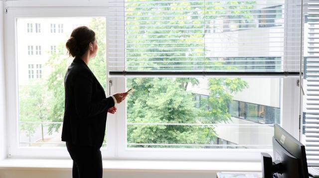 FILED - 09 July 2021, Berlin: A woman stands in an office by the window and makes a phone call via a headset. The top female managers of Germany's largest companies earned significantly less in 2024 and fell behind their male colleagues, according to the findings of a study by the consulting firm EY which was seen by dpa. Photo: Annette Riedl/dpa