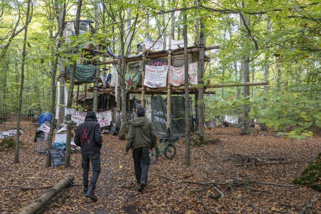 21 October 2025, Hesse, Langen: Two activists walk through a tree house settlement near the Langener Waldsee lake. Environmentalists have been protesting here for months against the planned clearing of the area where gravel is to be mined in the future. Photo: Boris Roessler/dpa