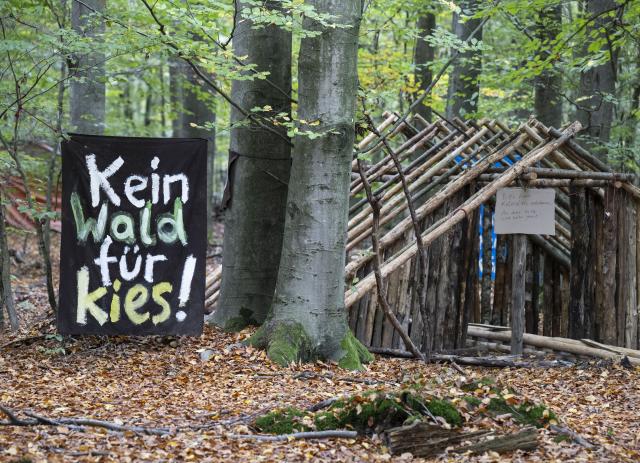 21 October 2025, Hesse, Langen: A sign reading "No forest for gravel" stands in a tree house settlement near the Langener Waldsee lake. Environmentalists have been protesting here for months against the planned clearing of the area where gravel is to be mined in the future. Photo: Boris Roessler/dpa