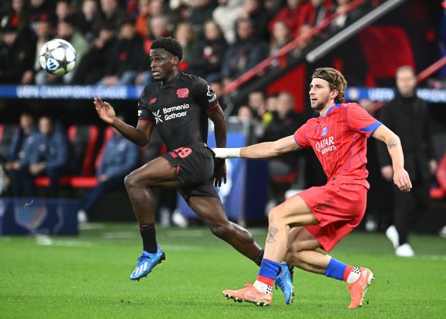 21 October 2025, North Rhine-Westphalia, Leverkusen: Leverkusen's Ernest Poku (L) and Paris Saint-Germain's Illya Zabarnyi battle for the ball  during the UEFA Champions League soccer match match between Bayer Leverkusen and Paris Saint-Germain at BayArena. Photo: Bernd Thissen/dpa