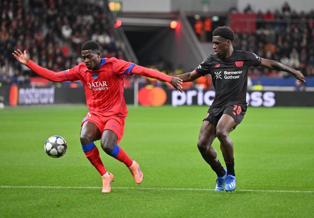 21 October 2025, North Rhine-Westphalia, Leverkusen: Paris Saint-Germain's Nuno Mendes (L) and Leverkusen's Ernest Poku in action during the UEFA Champions League soccer match match between Bayer Leverkusen and Paris Saint-Germain at BayArena. Photo: Bernd Thissen/dpa