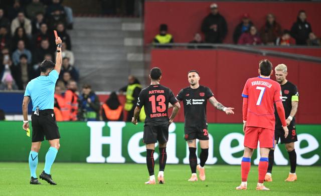 21 October 2025, North Rhine-Westphalia, Leverkusen: Referee Jesus Gil Manzano shows a red card to Leverkusen's Robert Andrich (r) during the UEFA Champions League soccer match between Bayer Leverkusen and Paris Saint-Germain at BayArena. Photo: Bernd Thissen/dpa