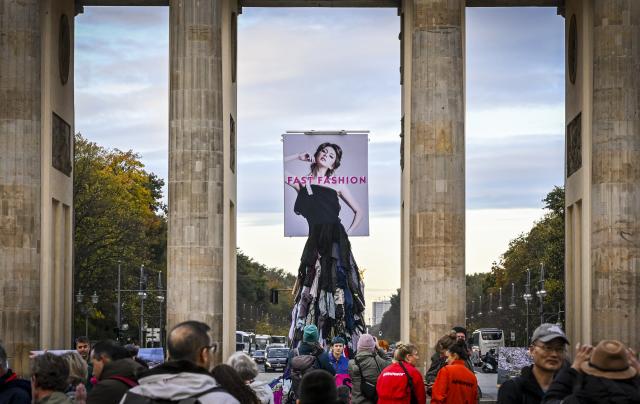 22 October 2025, Berlin: The environmental organization Greenpeace stages a protest against the fast fashion trend with a five-metre-high installation in front of the Brandenburg Gate. The activists are calling for an anti-fast fashion law. Photo: Jens Kalaene/dpa