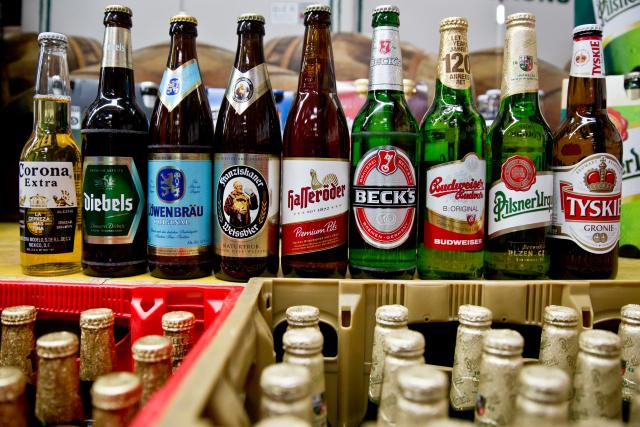 FILED - 13 October 2015, Bavaria, Nuremberg: Beer bottles of the Anheuser-Busch Inbev group of the brands (L-R) Corona, Diebels, Loewenbraeu, Franziskaner, Hasseroeder, Beck's and Budweiser stand next to bottles of the Pilsner Urquell and Tyskie brands of the SABMiller group in Nuremberg. Decades after a legal dispute over the beer brands Bud and Bit, the world's largest brewing group, AB InBev, is bringing its lager beer back to the German market under the name Anheuser-Busch Bud. Photo: picture alliance / Daniel Karmann/dpa