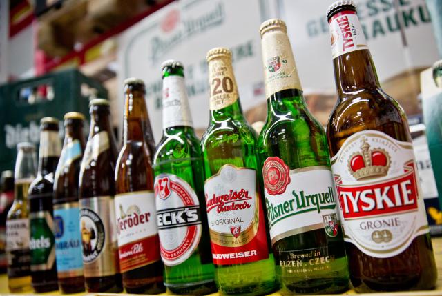 FILED - 13 October 2015, Bavaria, Nuremberg: Beer bottles of the Anheuser-Busch Inbev group of the brands (L-R) Corona, Diebels, Loewenbraeu, Franziskaner, Hasseroeder, Beck's and Budweiser stand next to bottles of the Pilsner Urquell and Tyskie brands of the SABMiller group in Nuremberg. Decades after a legal dispute over the beer brands Bud and Bit, the world's largest brewing group, AB InBev, is bringing its lager beer back to the German market under the name Anheuser-Busch Bud. Photo: picture alliance / dpa