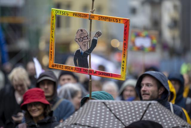 23 October 2025, North Rhine-Westphalia, Cologne: People hold placards and flags during a rally against Chancellor Merz's statements on the cityscape and migration in cologne. Photo: Thomas Banneyer/dpa