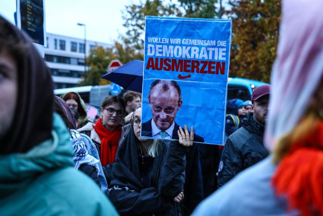 23 October 2025, North Rhine-Westphalia, Muenster: People hold placards and flags during a rally against Chancellor Merz's statements on the cityscape and migration in Muenster. Photo: Alex Talash/dpa