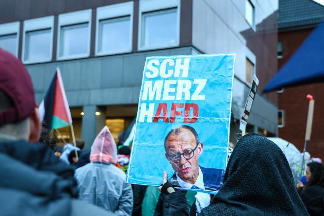 23 October 2025, North Rhine-Westphalia, Muenster: People hold placards and flags during a rally against Chancellor Merz's statements on the cityscape and migration in Muenster. Photo: Alex Talash/dpa