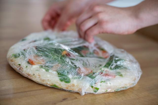 FILED - 24 June 2025, Baden-Württemberg, Stuttgart: A person unwraps a frozen pizza. Photo: Marijan Murat/dpa