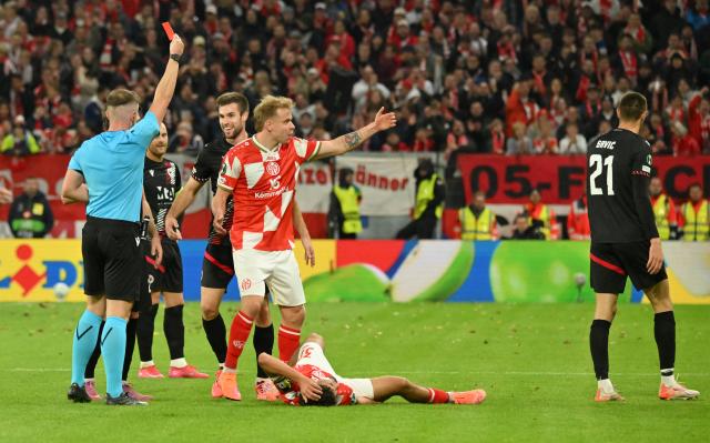 23 October 2025, Rhineland-Palatinate, Mainz: Referee Jamie Robinson (L) shows Zrinjski Mostar'S Igor Savic the red card during the UEFA Europa Conference League match between FSV Mainz 05 and Zrinjski Mostar at Mewa Arena. Photo: Torsten Silz/dpa