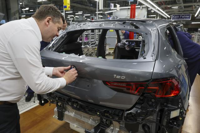 24 October 2025, Saxony, Leipzig: Sven Schulze, Saxony-Anhalt's Minister of Economic Affairs, affixes the BMW logo to a 1 Series at the BMW Group plant in Leipzig. Around 6800 employees currently produce the 1 Series, the 2 Series Gran Coupe, the 2 Series Active Tourer and the Mini Countryman in Leipzig. Photo: Jan Woitas/dpa