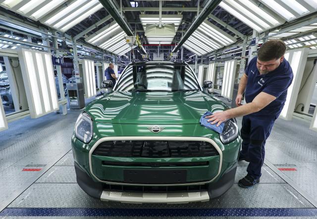 24 October 2025, Saxony, Leipzig: An employee at the BMW Group plant in Leipzig checks a BMW Mini Countryman in the light tunnel. Around 6800 employees currently produce the 1 Series, the 2 Series Gran Coupe, the 2 Series Active Tourer and the Mini Countryman in Leipzig. Photo: Jan Woitas/dpa