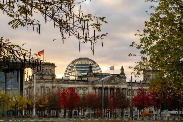 25 October 2025, Berlin: In front of the German Reichstag building there are trees with red and yellow leaves in the fall. Photo: Christophe Gateau/dpa