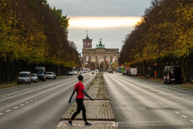25 October 2025, Berlin: A jogger looks towards the Brandenburg Gate at sunrise. Photo: Christophe Gateau/dpa