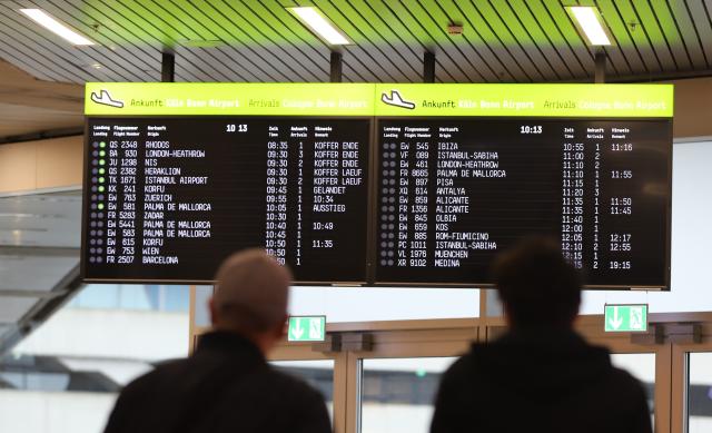 25 October 2025, North Rhine-Westphalia, Cologne: People stand in front of a display board showing arriving flights at Cologne/Bonn Airport, as the two-week fall vacation in North Rhine-Westphalia comes to an end. Photo: Sascha Thelen/dpa
