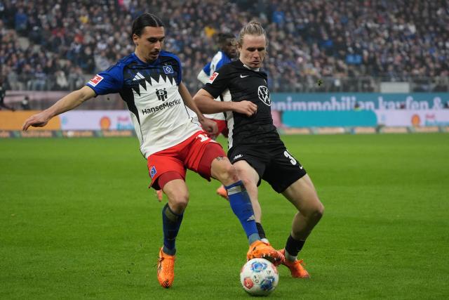 25 October 2025, Hamburg: Hamburger's Rayan Philippe (L)and Wolfsburg's Patrick Wimmer battle for the ball during the German Bundesliga soccer match between Hamburger SV and VfL Wolfsburg at the Volksparkstadion. Photo: Marcus Brandt/dpa - IMPORTANT NOTICE: DFL and DFB regulations prohibit any use of photographs as image sequences and/or quasi-video.