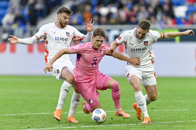 25 October 2025, Sinsheim: Heidenheim's Julian Niehues and  Patrick Mainka (L) battle for the ball with Hoffenheim's Alexander Prass during the German Bundesliga soccer match between TSG 1899 Hoffenheim and 1. FC Heidenheim at the PreZero Arena. Photo: Uwe Anspach/dpa - IMPORTANT NOTICE: DFL and DFB regulations prohibit any use of photographs as image sequences and/or quasi-video.