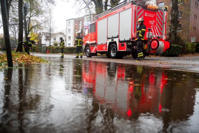 26 October 2025, Hamburg: Firefighters stand by a flooded street in the Lohbruegge district after heavy rain. Photo: Daniel Bockwoldt/dpa
