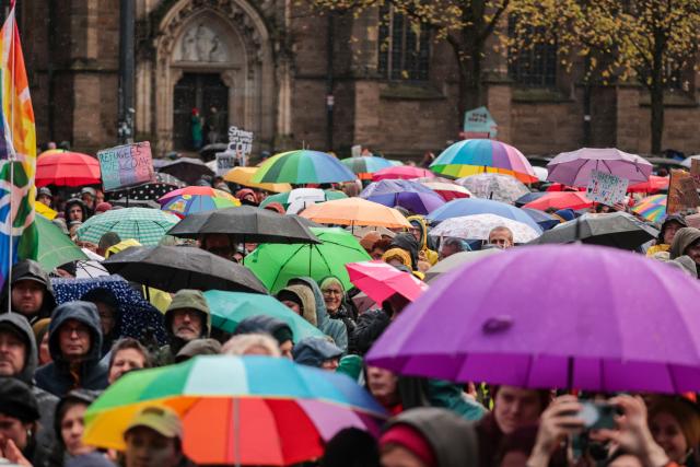 26 October 2025, Bremen: People with umbrellas take part in a rally at the Domshof against statements by German Chancellor Friedrich Merz on the cityscape and migration. Photo: Focke Strangmann/dpa