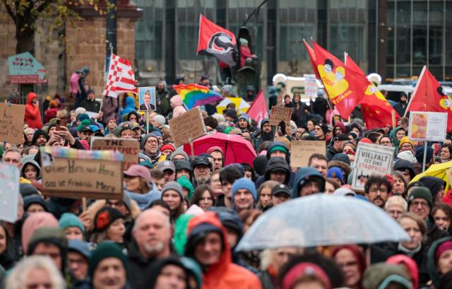 26 October 2025, Bremen: People with umbrellas and flags take part in a rally at the Domshof against statements by German Chancellor Friedrich Merz on the cityscape and migration. Photo: Focke Strangmann/dpa