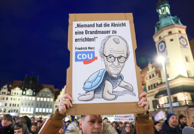 27 October 2025, Saxony, Leipzig: A person holds a placard on the market square with the inscription "Nobody intends to build a firewall" during a demonstration entitled "The cityscape remains colorful" against statements by German Chancellor Friedrich Merz on the "cityscape" and migration. Photo: Jan Woitas/dpa