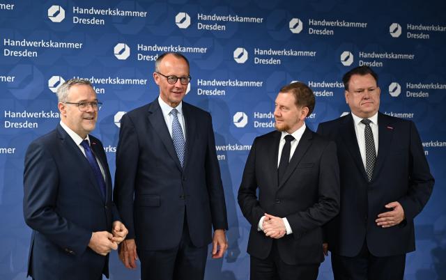 28 October 2025, Saxony, Dresden: (L-R) Joerg Dittrich, President of the Dresden Chamber of Skilled Crafts and the German Confederation of Skilled Crafts (ZDH), German Chancellor Friedrich Merz, Saxony's Minister President Michael Kretschmer, and Andreas Brzezinski, Managing Director of the Dresden Chamber of Skilled Crafts, talk at the training center of the Dresden Chamber of Skilled Crafts. Photo: Hendrik Schmidt/dpa