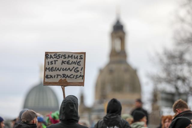 28 October 2025, Saxony, Dresden: A demonstrator holds a sign reading "Racism is not an opinion! Exit: Racism" at a demonstration during German Chancellor Friedrich Merz's inaugural visit to the Saxon State Chancellery. Photo: Jan Woitas/dpa